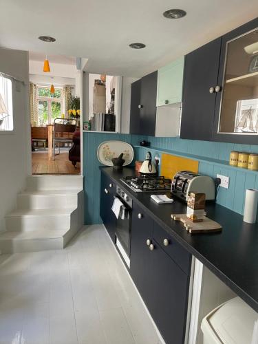 a kitchen with black counters and blue cabinets at Telagraph cottage in Penzance