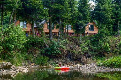 a person in a kayak on a river in front of a house at Novosiele Residence - nad górską rzeką - Leśne Spa sauna jacuzzi - Bieszczady in Bystre