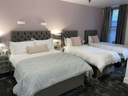 a bedroom with two beds with white sheets at Atlantic Lodge, Main Street Ardara in Ardara