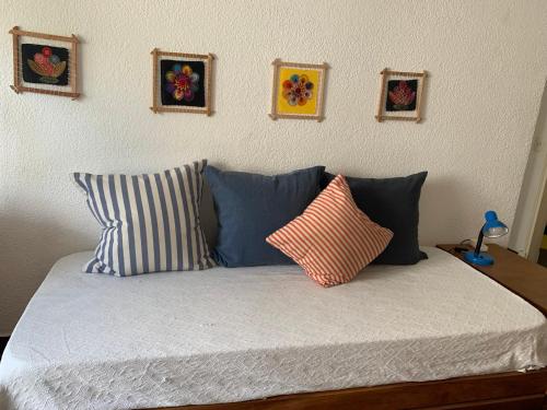 a bed with blue pillows and pictures on the wall at Lindo apartamento cerca del mar, Pinamar in Pinamar