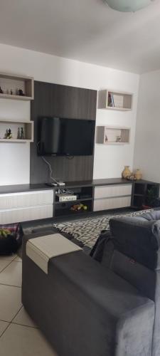 uma sala de estar com um sofá e uma televisão em Aconchego em Chapecó