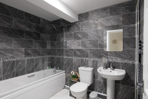 La salle de bains est pourvue de toilettes blanches et d'un lavabo. dans l'établissement homely - North London Apartments Wembley, à Harrow on the Hill