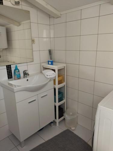 a white bathroom with a sink and a mirror at Apartman Barada in Slatine