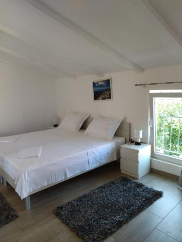 a bedroom with a large white bed and a window at Apartman Barada in Slatine