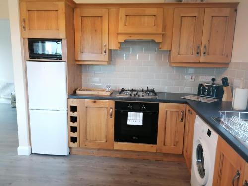 a kitchen with wooden cabinets and a black stove top oven at Atlantic way Apartment in Sligo