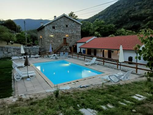 a swimming pool in front of a stone house at Quinta de Leandres in Manteigas