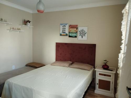 um quarto com uma cama branca e uma cabeceira vermelha em Casa c/ Piscina e Área Gourmet, 5 min da praia. em Guarapari