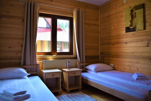 two twin beds in a room with a window at Srna Chalet - Rooms in Žabljak