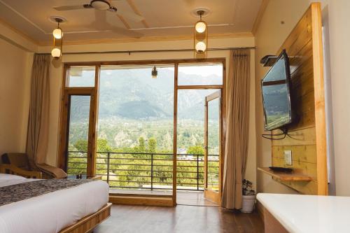 1 dormitorio con ventana grande con vistas a la montaña en Niranya Guest House, en Katrain