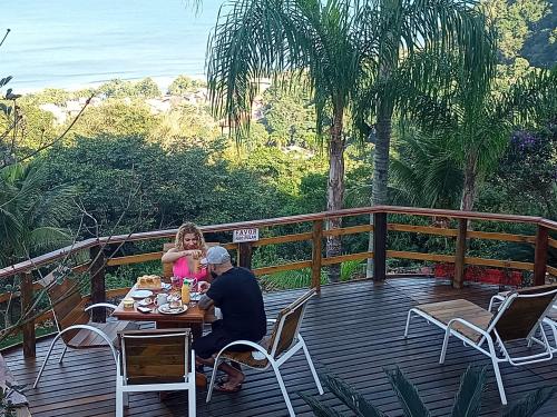 a man and a girl sitting at a table on a deck at Vila Lia in São Sebastião