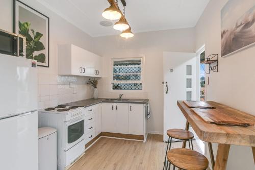 eine Küche mit weißen Geräten und einem Holztisch in der Unterkunft Snapper Rocks Studio Number 10 - Wi-Fi Included in Tweed Heads