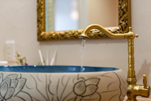 a bathroom sink with water pouring from a gold faucet at Palm Villa Ishigakijima karei in Ishigaki Island