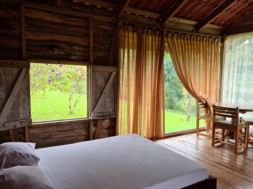 1 dormitorio con cama, mesa y ventana en Santa Maria Volcano Lodge, en Hacienda Santa María