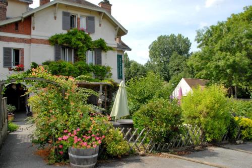a garden with an umbrella and flowers in front of a house at Logis H&ocirc;tel De La Chapelle in Milon-la-Chapelle