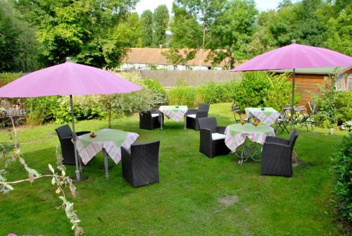 a group of tables and chairs with umbrellas in a yard at Logis Hôtel De La Chapelle in Milon-la-Chapelle