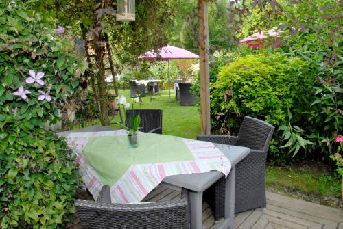 a table and chairs with a green tablecloth on a patio at Logis Hôtel De La Chapelle in Milon-la-Chapelle