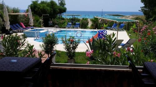 a swimming pool with chairs and the ocean in the background at Hotel Grün in Kızılot