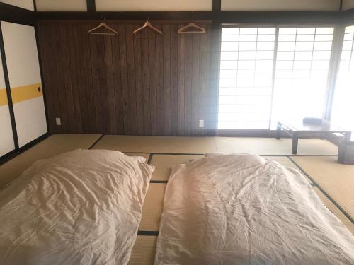 a bedroom with two beds with white sheets on the floor at Mt Fuji Historical Oshi house hitsuki in Fujiyoshida