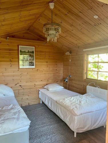 two beds in a wooden room with a chandelier at Villa i Norrtälje in Norrtälje