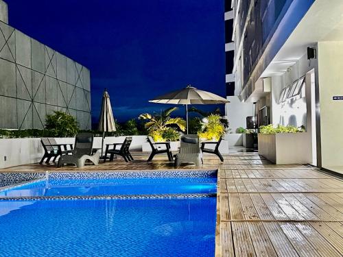 a swimming pool with chairs and an umbrella next to a building at Inspiria in Davao City