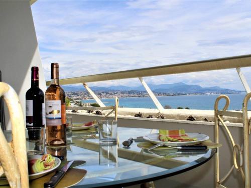 une table avec des bouteilles de vin et des verres sur un balcon dans l'établissement Bel Appartement 2P, Vue Mer, 4 Pers, Villeneuve-Loubet Plage - FR-1-252A-80, à Villeneuve-Loubet