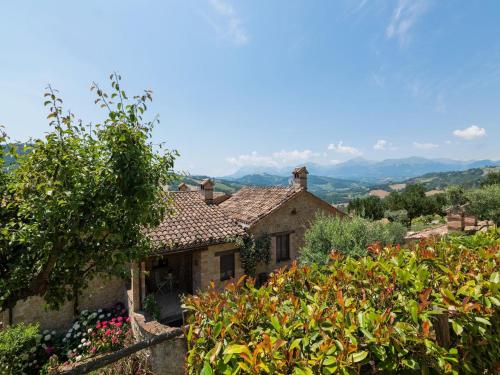 an old house in a garden with mountains in the background at Belvilla by OYO La Priora in Monte San Martino