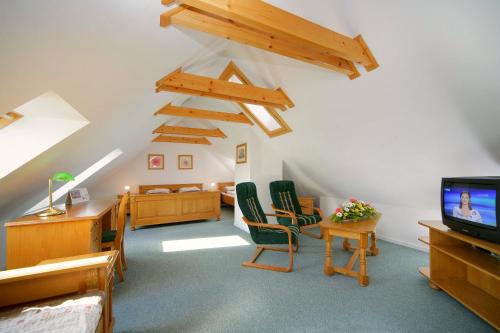 a attic room with green chairs and a tv at Penzion Kovárna in Bukvice