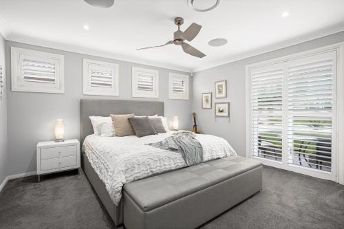 a bedroom with a bed and a ceiling fan at Little Lake Beach House - Beachside 4 Bedroom Luxury Home in Lake Illawarra
