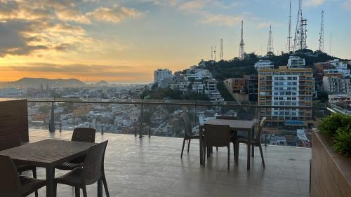 a table and chairs on a balcony with a view of a city at Malecón de Mazatlan Vista al mar Alberca Infinity Jacuzzi Gym in Mazatlán