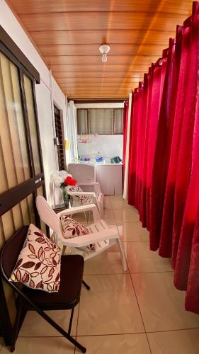 a room with two chairs and red curtains at Apartment 10 minutes by the SJO airport - in Alajuela