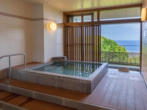 a bath tub in a room with a view of the ocean at KAMENOI HOTEL Atami Annex in Atami