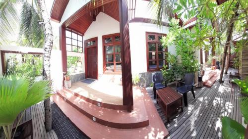 a house with a porch with trees and plants at Beach Cottage in Rasdu