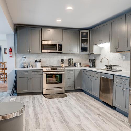 a kitchen with gray cabinets and stainless steel appliances at Winner's Getaway in Norwich