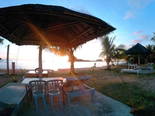 a table and chairs under an umbrella on the beach at MG Chateau Resort in El Nido