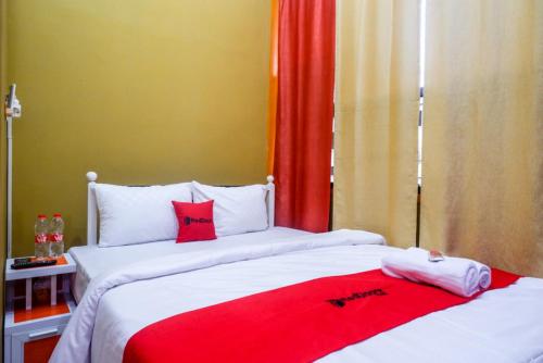 two beds in a room with red and white at RedDoorz Syariah near Exit Toll Ngemplak Solo in Sawahan