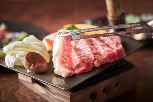 a plate of meat and vegetables on a table at Fumoto Ryokan in Minamioguni