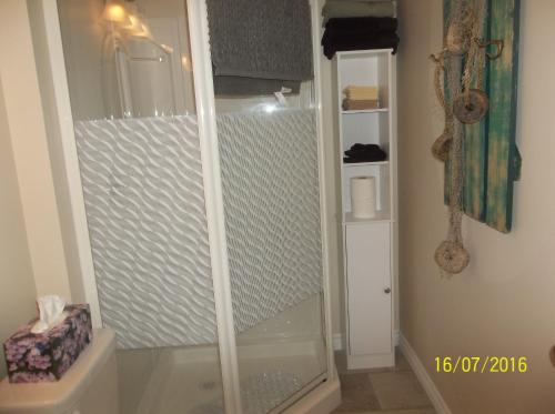 a shower with a glass door in a bathroom at Cottage Jasmine on the Shediac Bay with hot tub in Shediac