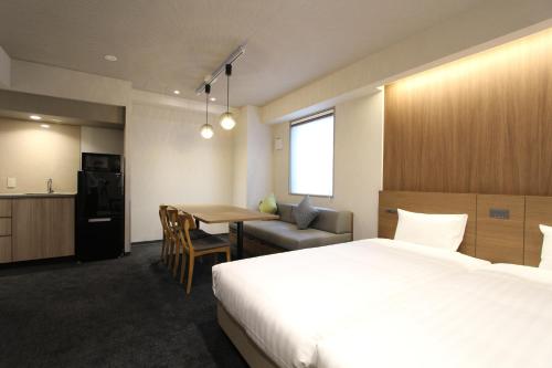une chambre d'hôtel avec un lit, une table et une cuisine dans l'établissement KOKO HOTEL Residence Asakusa Tawaramachi, à Tokyo