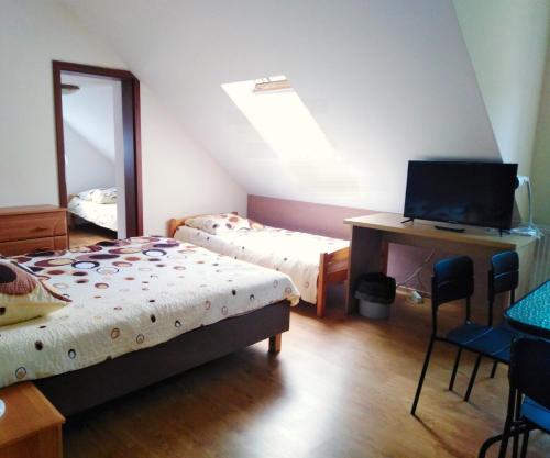 a bedroom with two beds and a desk with a computer at Piernikowy Dworek in Lubicz