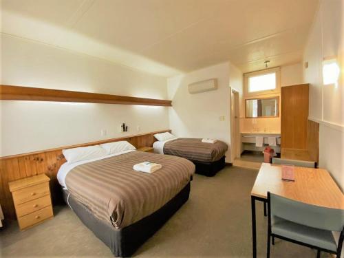 Cette chambre comprend deux lits, un bureau et une table. dans l'établissement The Terang Motor Inn, à Terang