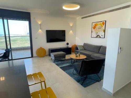 a living room with a couch and a table at #דירת יוקרה על הים Sunset Beach Apartment# in Giv‘at Olga