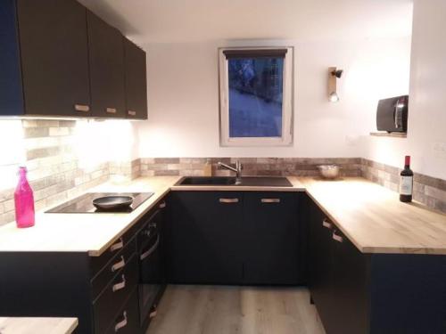 - une cuisine avec des placards noirs et une bouteille de vin dans l'établissement Appart lumineux historique de Bayonne Saint-Esprit, à Bayonne