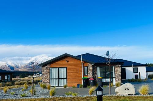 a log cabin with mountains in the background at Stellar Apartment in Lake Tekapo