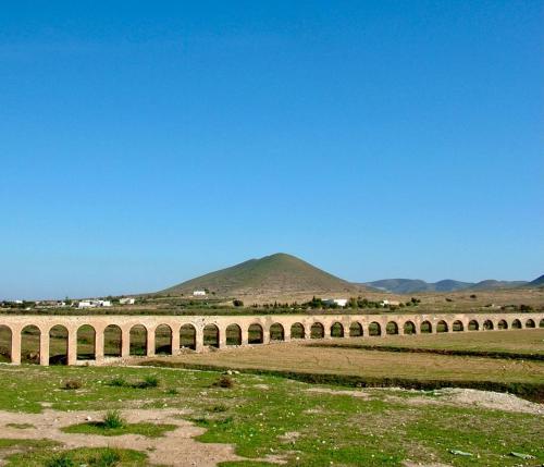 a bridge over a field with a mountain in the background at Alojamientos Tía María in Fernán Pérez