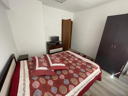 1 dormitorio con 1 cama con manta roja y blanca en Apartament Mioritza 2B en Horezu