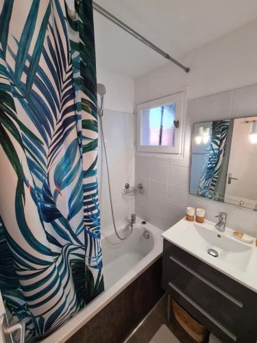 a bathroom with a tub and a sink and a shower curtain at Studio avec terasse vue mer in Porticcio