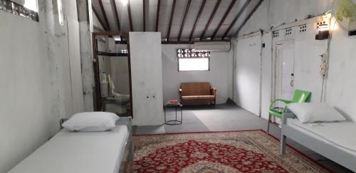 a room with two beds and a chair in it at Benara Shariah Homestay in Yogyakarta