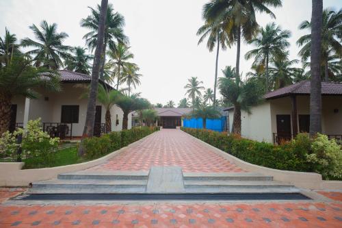 a brick road in front of a building with palm trees at Royal Destiny Resort in Malaiyāndipattanam