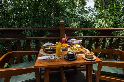 a wooden table with plates of food on it at Arkamara Dijiwa Ubud in Ubud