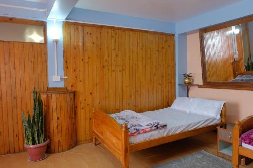 1 dormitorio con 1 cama con pared de madera en Down Town Homestay, en Kurseong